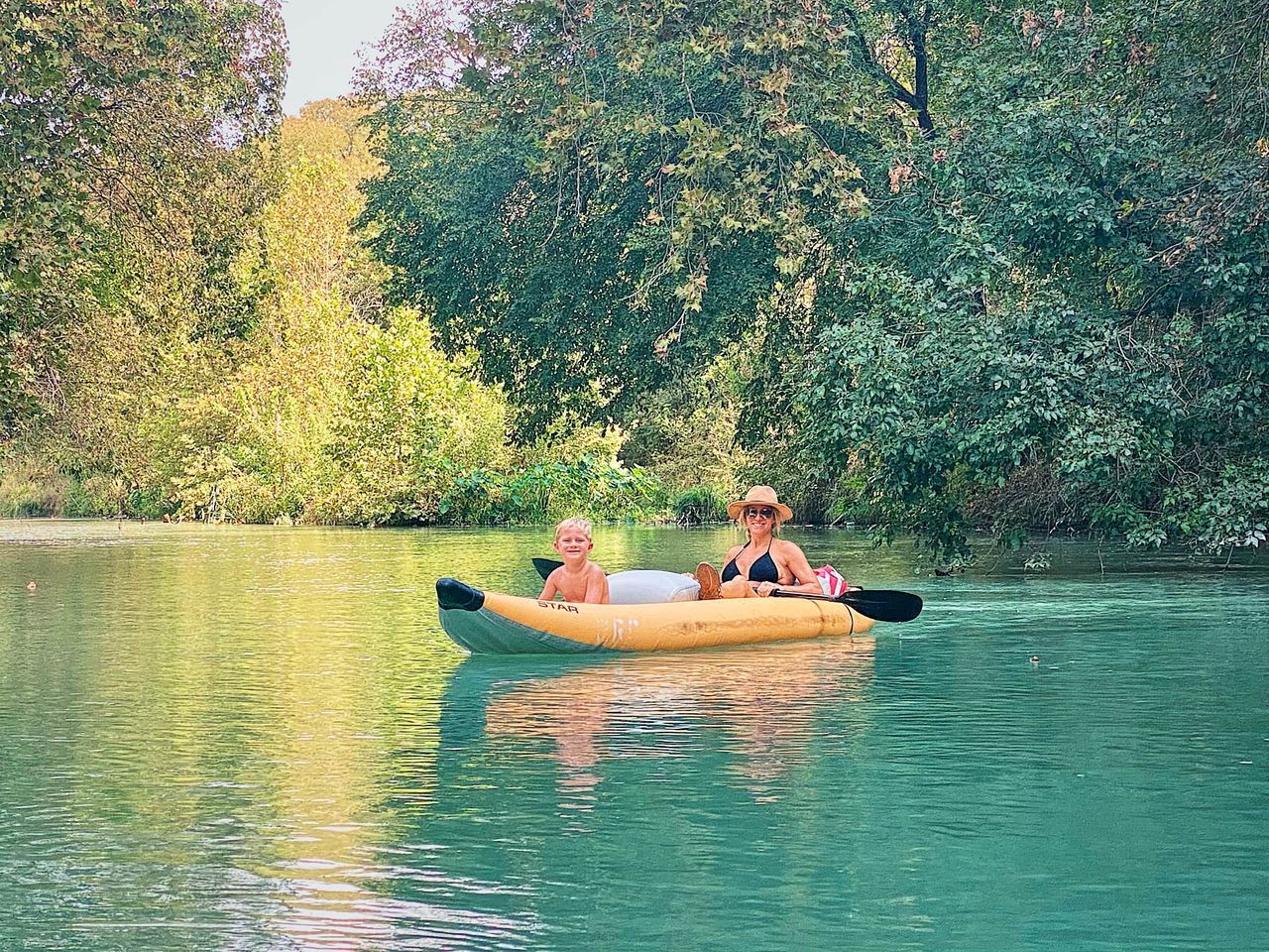 Un kayak sur une étendue d’eau calme, avec une végétation luxuriante en arrière-plan.