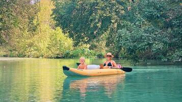 A kayak on a calm body of water with dense greenery in the background.