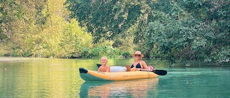 A kayak on a calm body of water with dense greenery in the background.