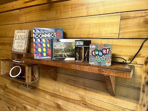 Una estantería de madera con juegos de mesa y un cartel.