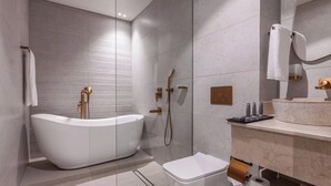 Un baño moderno con una bañera independiente, un inodoro y un tocador con espejo.