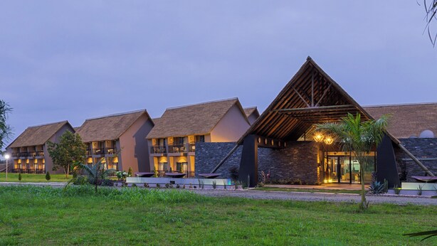 Un hotel con varias edificaciones, una estructura de techo de paja y una entrada bien iluminada.