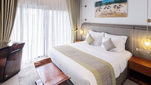Habitación de hotel con una cama grande, un escritorio, una silla y un cuadro en la pared.