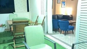 A room with a green artificial turf floor, a table with a candle, and a chair. - Cozy & Cute Apartment in Piraeus (Pireas)