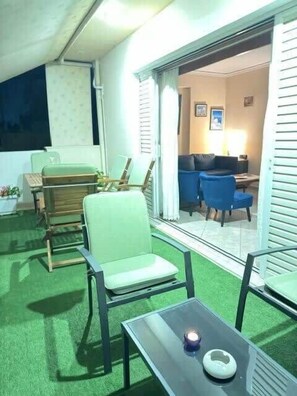 A room with a green artificial turf floor, a table with a candle, and a chair. - Cozy & Cute Apartment in Piraeus (Pireas)