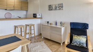 Une cuisine compacte avec des meubles en bois, un four à micro-ondes et un petit coin repas équipé de tabourets.