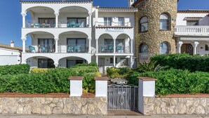 Un immeuble à plusieurs étages doté de balcons, d’une tour en pierre et d’une entrée fermée par un portail.