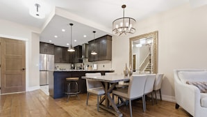 Une cuisine moderne avec des meubles de couleur sombre, un îlot central et des luminaires suspendus.