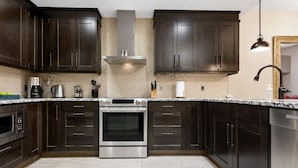 Une cuisine moderne avec des meubles en bois foncé, des appareils électroménagers en acier inoxydable et un dosseret carrelé.