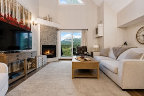 Ein Wohnzimmer mit Kamin, Fernseher, einer Couch und einem Couchtisch mit Snacks und Weingläsern.
