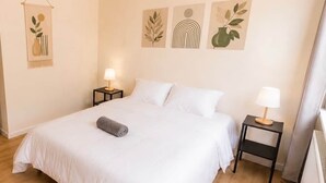 A neatly made bed with white linens, two bedside tables with lamps, and three wall-mounted artworks. - 8. Snooze 8H Brussels Charleroi Airport (Charleroi)