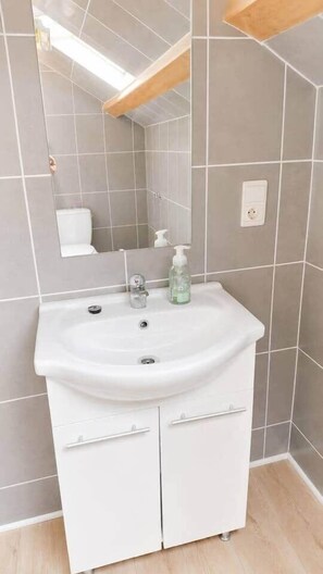Ein Badezimmer mit einem weißen Waschbecken, einem Spiegel und einer Handseifenflasche.