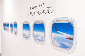 Eine Wand mit einer Reihe von Flugzeugfenstern und einem Schild mit der Aufschrift 'ENJOY THE moment'.