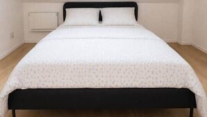 Ein Schlafzimmer mit Bett, Fenster und Heizkörper.