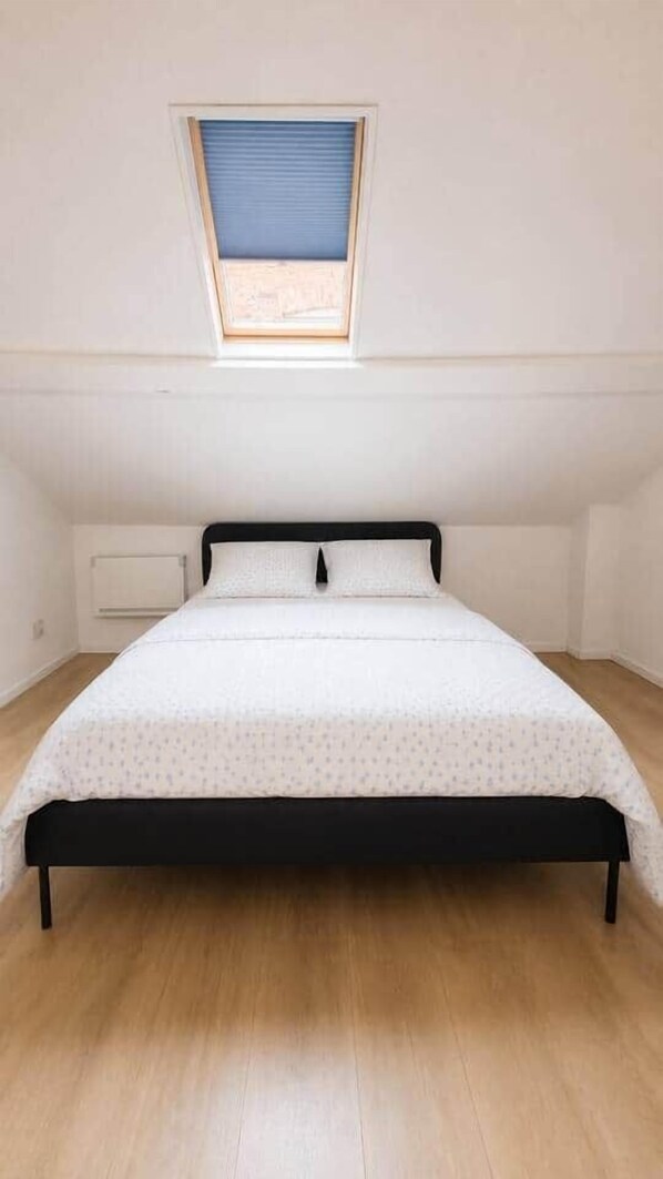 Ein Schlafzimmer mit Bett, Fenster und Heizkörper.