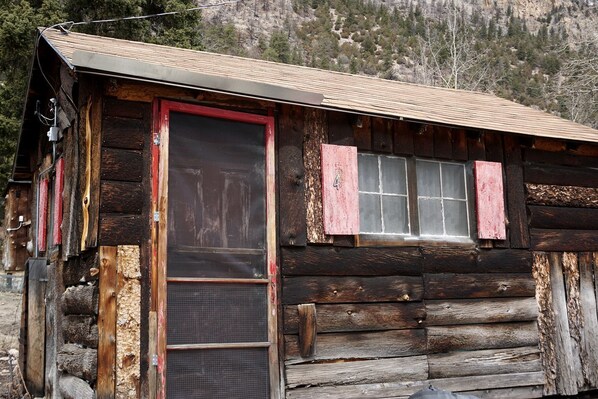 A rustic log cabin with a red door, a window with shutters, and a number '4' on the wall.