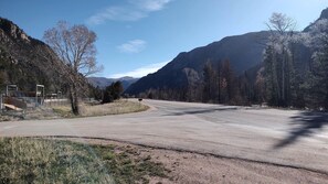 A road curving through a mountainous area with sparse trees and a clear sky.