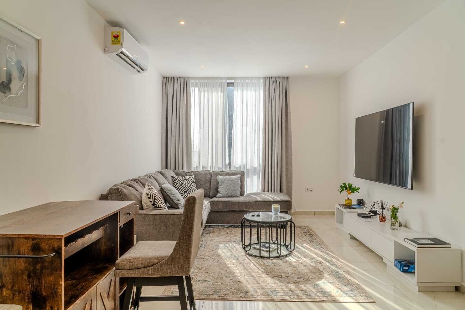 A modern living room with a sofa, a coffee table, a TV, and a desk.