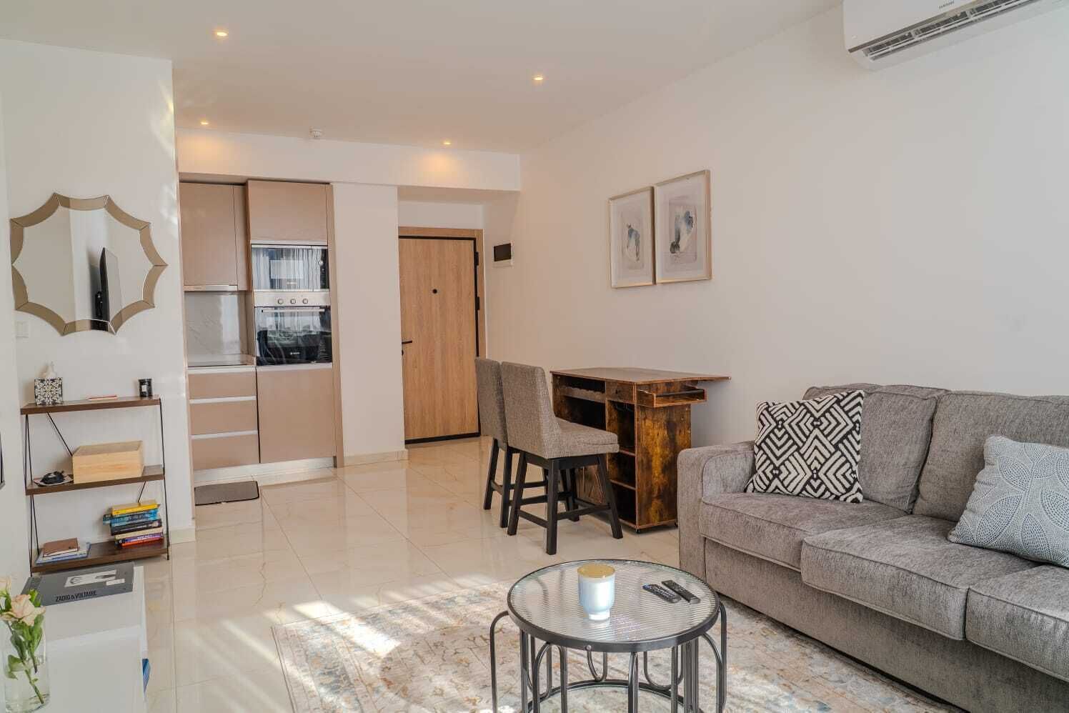 Una sala moderna con sofá, una mesa de centro y un comedor con sillas.