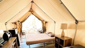 A tent with a bed, a desk, and a chair. - Unforgettable Aquatic Adventure for the Whole Family: Cute Safari Tent on the San Marcos River near Kingsbury, Texas (Kingsbury)