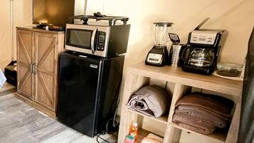 Uma cozinha compacta com geladeira, micro-ondas, liquidificador e cafeteira.