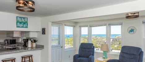 A spacious living area with a view of the ocean, a kitchen with modern appliances, and a cozy seating arrangement.