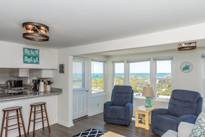 A spacious living area with a view of the ocean, a kitchen with modern appliances, and a cozy seating arrangement. - Sea Breeze enjoy oceanviews and a charming 3-bedroom retreat in Surf City. (Surf City)