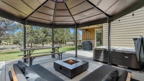 Une terrasse extérieure avec un foyer, des sièges et un barbecue.