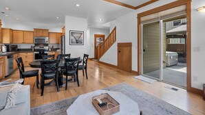 Une cuisine spacieuse avec des meubles en bois, un coin repas avec une table et des chaises, et un escalier menant à une mezzanine.