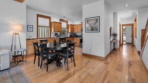 Une cuisine spacieuse avec des meubles en bois, un coin repas avec une table ronde et des chaises, et un escalier menant à un autre niveau.