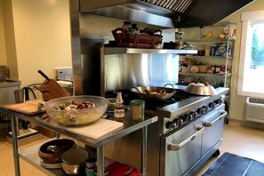 Uma cozinha com eletrodomésticos de aço inoxidável, uma tigela grande no balcão e uma janela com vista.