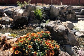 Um jardim com pedras, um pequeno lago e plantas floridas.