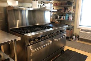 Eine Küche aus Edelstahl mit Gaskochfeld, Backofen und einer eingebauten Ablage mit verschiedenen Küchenutensilien.
