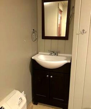 Een badkamer met een wit wastafelmeubel, donkere kastjes en een spiegel erboven.