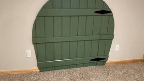 Un mur vert en forme d’arche, doté d’un motif texturé, une prise électrique blanche et un objet noir fixé au mur.