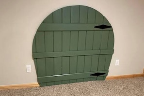 Un mur vert en forme d’arche, doté d’un motif texturé, une prise électrique blanche et un objet noir fixé au mur.