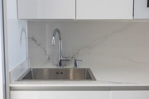 Eine moderne Küche mit Spüle aus Edelstahl, weißen Schränken und einer Marmor-Spritzschutzwand.