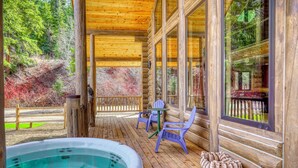 Eine Holzterrasse mit Whirlpool, Stühlen und Hundebett.