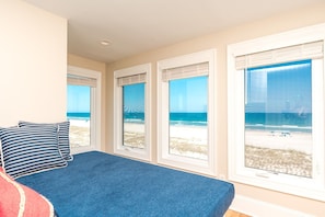 A bedroom with a bed, a window with a beach view, and a window with a beach view. - Seascape - 4BR, Oceanfront, Dog Friendly, Fully Renovated! (Topsail Beach)