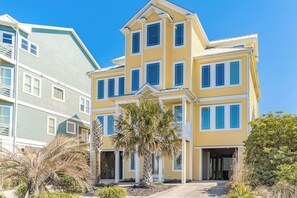 A multi-story residential building with a prominent entrance, a covered porch, and a garage. - Sea Escape - Incredible Oceanfront 8 BR Home in Gated Community (North Topsail Beach)