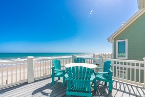 A wooden deck with a table and chairs, overlooking a beach. - Sea Escape - Incredible Oceanfront 8 Bedroom Home in Gated Community (North Topsail Beach)