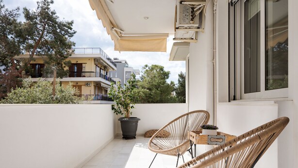 A balcony with two wicker chairs, a small table, and a potted plant. - Voula Calm Living (Voula)