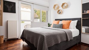A bedroom with a bed, a radiator, a window, and a wall-mounted shelf. - Voula Calm Living (Voula)
