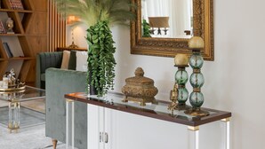 A console table with a mirror, decorative items, and a sofa in the background. - Voula Calm Living (Voula)