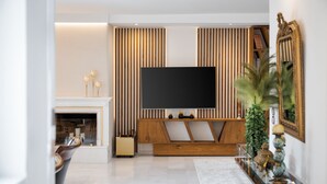 A modern living room with a flat-screen TV, a fireplace, and a wooden entertainment unit. - Voula Calm Living (Voula)