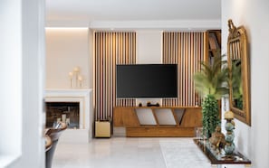 Ein modernes Wohnzimmer mit Fernseher, Kamin und einer Holz-Unterhaltungsecke.