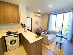 Ein kompaktes Apartment mit Küchenzeile, Essbereich, Sofa und Balkon.