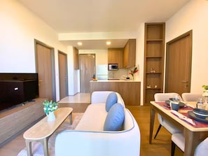 Ein modernes Wohnzimmer mit einer Couch, einem Esstisch und einer Küche im Hintergrund.