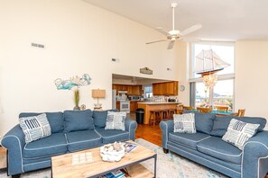 Ein Wohnzimmer mit zwei Sofas, einem Couchtisch und einer Küche im Hintergrund.