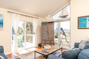 Ein Wohnzimmer mit einem Holzkabinett, einem Teleskop, einem grünen Sessel und einem Sofa.